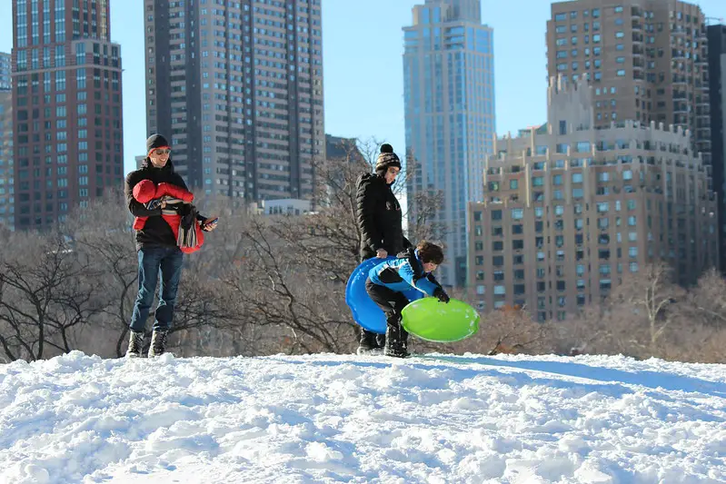 Family with Kids Sledding on the Snow in Central Park, New York City