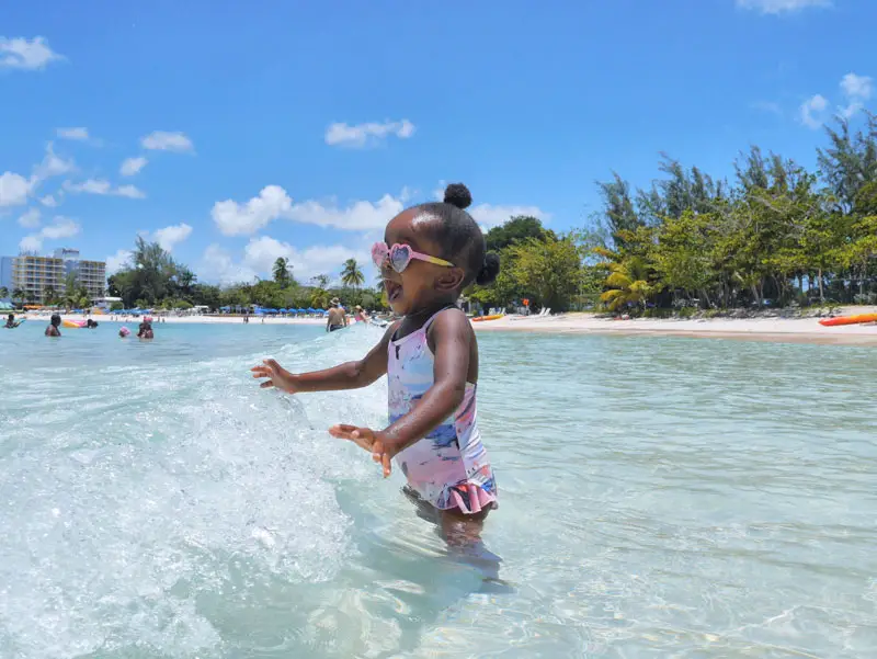 Toddler Girl Splashing in Waves on Pebbles Beach, Barbados